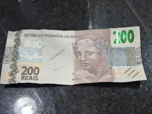 A nota falsificada foi constatada através de uma caneta detectora de cédulas falsas (GCM)